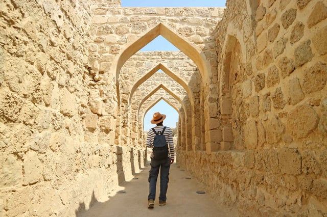 Tourist walking through ancient Bahrain arches